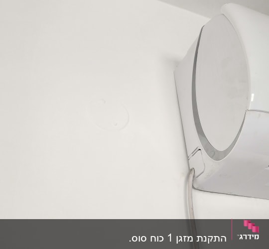 מזגן מותקן על קיר לבן עם כבל חשמל
